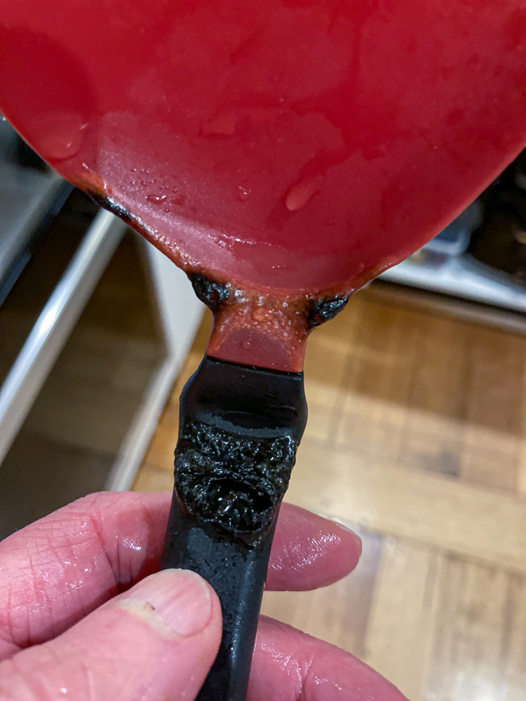 Barb holding a black and red spatula that melted during cooking