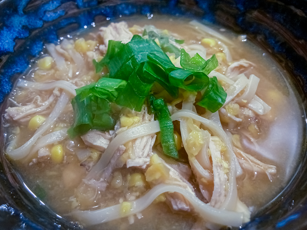 Sweetcorn, chicken and egg noodle soup, garnished with spring onions from the book In Praise of Veg