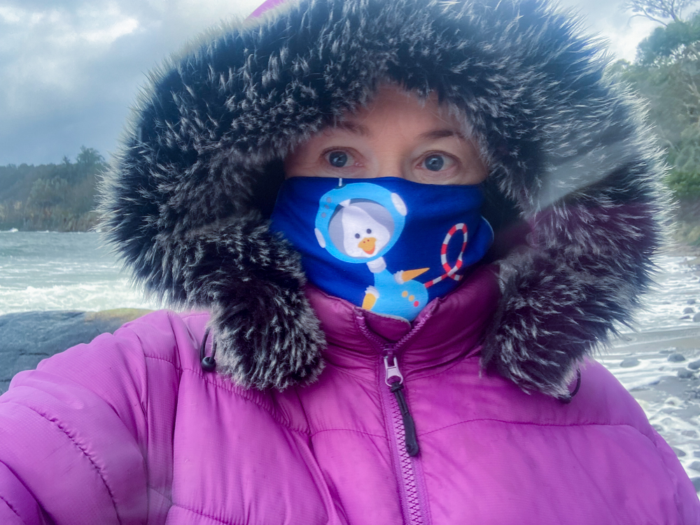 Barb wearing a facemask and a purple pufferjacket outside in stormy weather