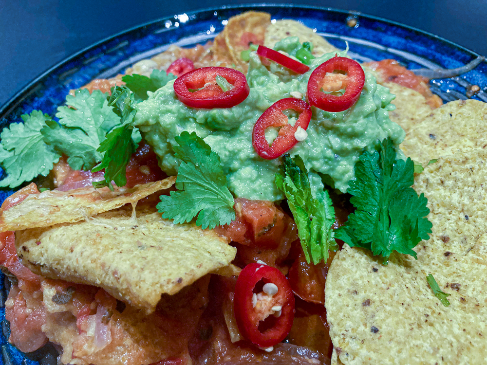 Tomato nachos with corn chips, guacamole & topped with chilli