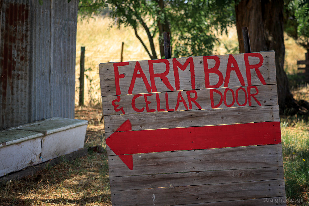 Hand painted red lettering on a wooden pallet FARM BARB & CELLAR DOOR with a left-pointing arrow
